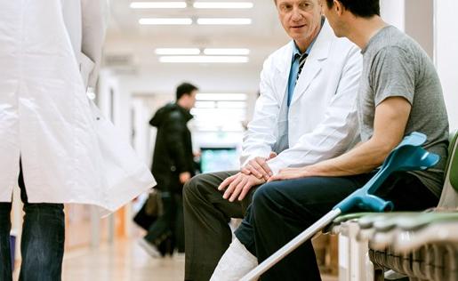 A man with crutches talking to his doctor in a hospital